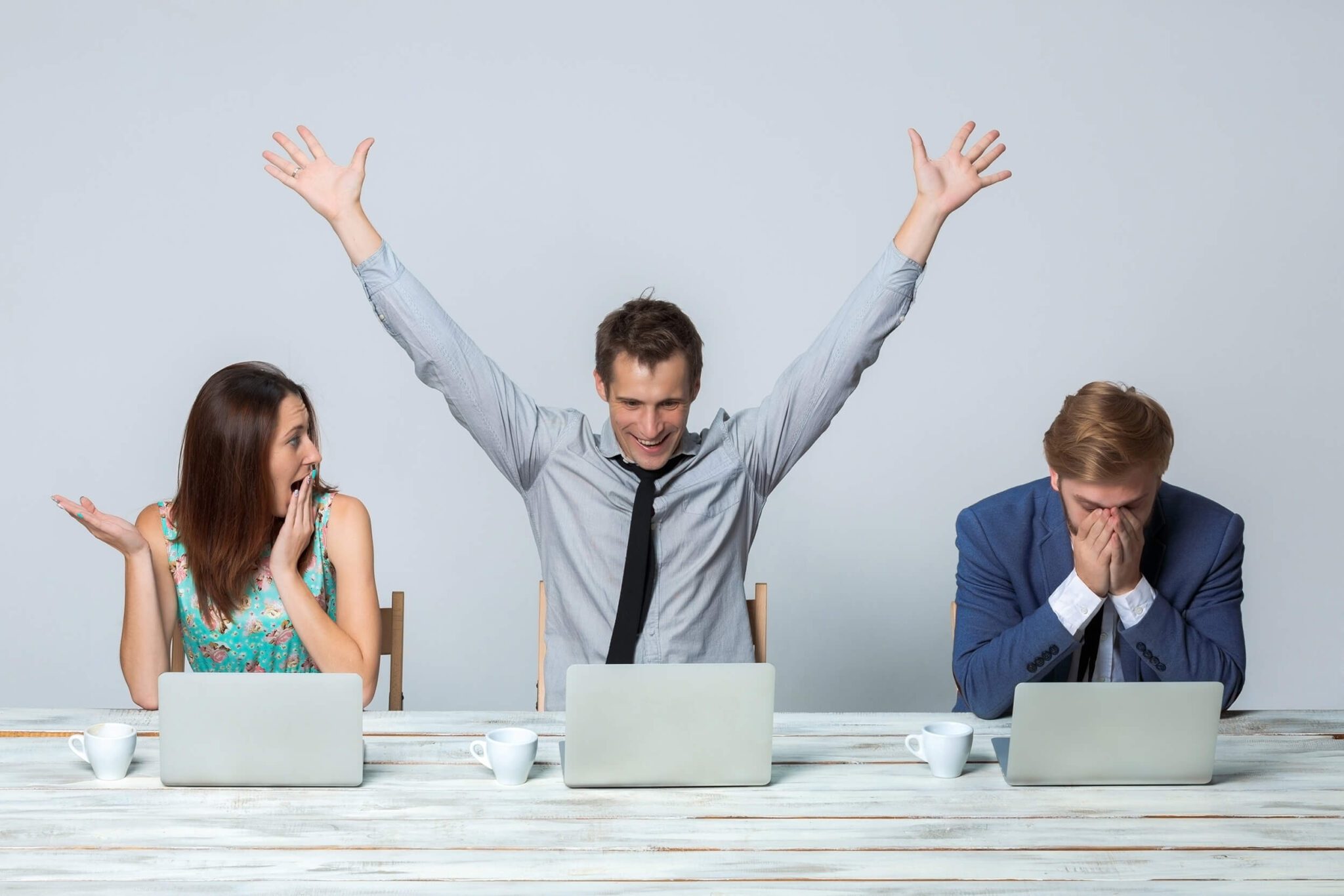 A woman and two men are in front of their laptops looking at cartoons in PowerPoint presentations.