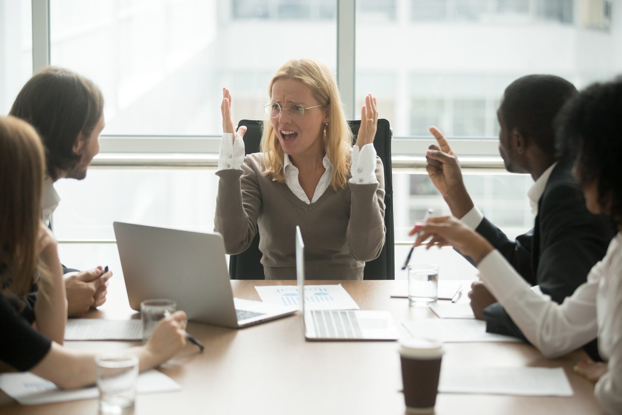 The white business woman in the meeting is feeling the emotion of frustration.
