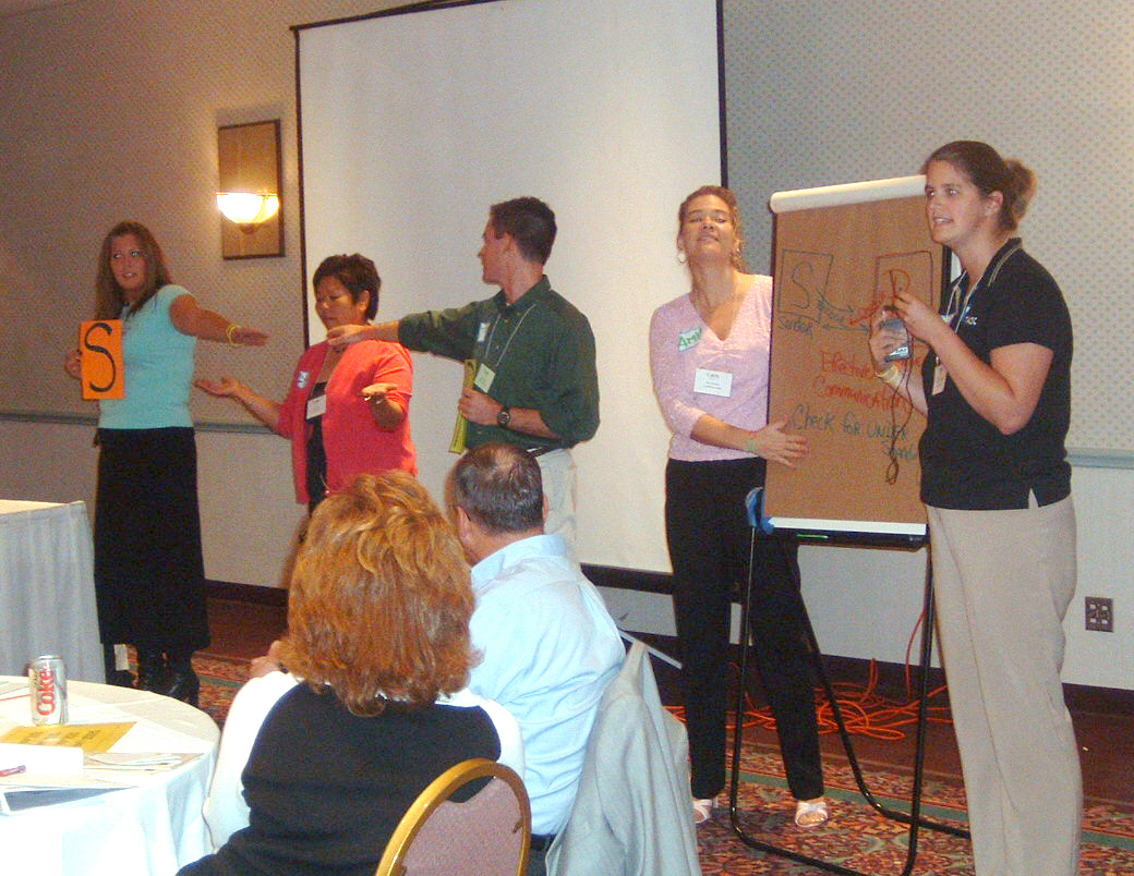 The training participants are reporting out their small groups' ideas on flip charts.